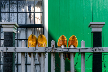 Wooden shoes on a fence in front of a green wooden houseの写真素材