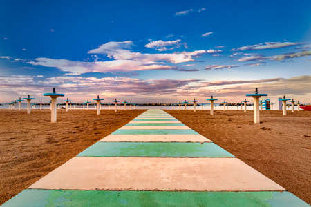 Beach with walkway and tables, bathhouse, end of season, tables without umbrellasの写真素材