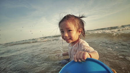 The girl play in the sea with sand bucket (Action Camera)の写真素材