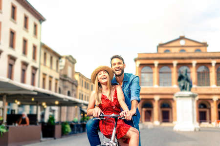 Couple riding bicycle in the city street - concept about two smiling young sweethearts who see and show the wayの写真素材