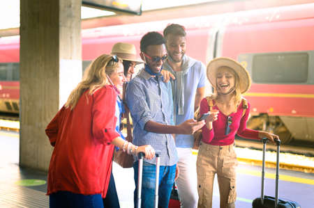 Friends buy online reservations at subway - Young people using mobile telephone too take a selfie - Travel, youth lifestyle, holidays and wanderlust conceptの写真素材