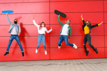 Young people having fun around city street during coronavirus outbreak - Happy friends wearing face protective masks and laughing together - New normal lifestyle concept happy teenagerの写真素材