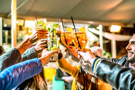 Group of happy friends drinking and toasting cocktail at bar - Friendship concept with young people having fun together while drinking mojito - Focus on middle glassの写真素材