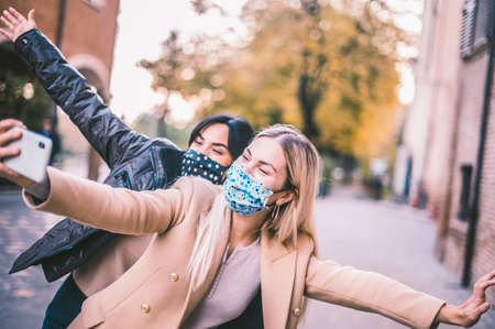 Multi ethnic Friends having fun in city taking selfie with face mask in coronavirus time - New normal lifestyle conceptの写真素材
