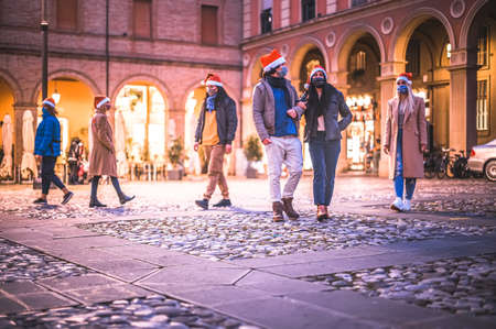 Group of people wearing face mask and santa hat walking in road in the Christmas night in...