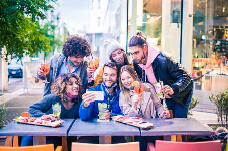 Friends taking selfie outside at cocktail bar - New normal lifestyle concept with young people having fun together at restaurant with face masksの写真素材