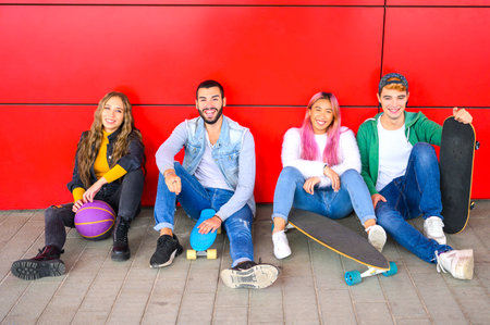 Group of students sitting on the floor outside the school - Friends with skateboard sitting at parkの写真素材