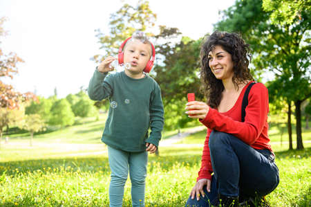 Smiling young mother with her beautiful son take a selfie photo in the garden - Funny, joy, cute, lovely concept about little happy boy eat an apple the girl drink coffeeの写真素材