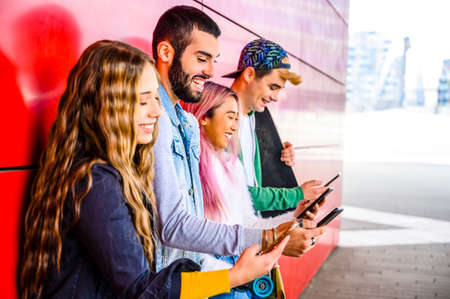 Happy young multiracial people meeting outdoors - Group of cheerful teenagers having fun and watching smart mobile phones, concepts about teenage, lifestyle and generation z - Main focus on beard guyの写真素材