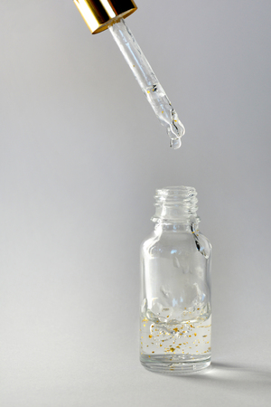 Gold particles glittering serum bottle with dropperの写真素材