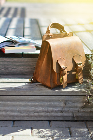 vintage style natural leather brown backpack and books on gray rustic wooden stairsの写真素材