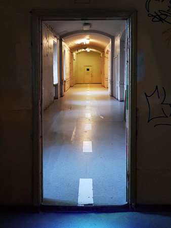 Vintage rustic warm lighted tunnel with white dotted line leading forward the door in the endの写真素材