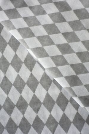 White and grey rhombus harlequin pattern fabric sample. Folded fabric backgroundの写真素材