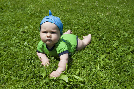 A bit sad boy on the green grassの写真素材