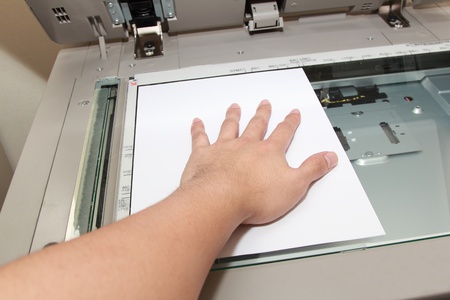 hand pressing paper on a copy machine