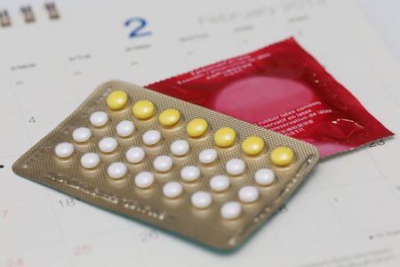 birth control pills and condom on a calendarの写真素材