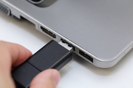 background of hand connecting thumb drive to laptop usb port