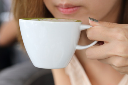 close-up image of woman drinking japanese matcha green tea latteの写真素材