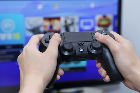 THAILAND -OCTOBER 2: Hand Playing Sony Dualshock 4 Controller for PlayStation 4 with the Screen on...