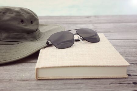 travel and vacation concept of camera sunglasses hat  and book on the wooden floorの写真素材