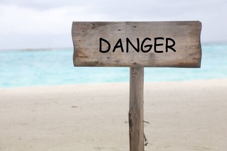 wooden sign with word danger on the beachの写真素材