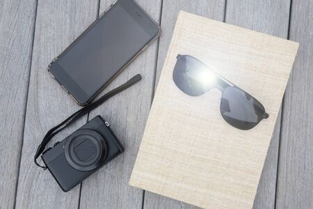 travel and vacation concept of camera sunglasses and book on the wooden floorの写真素材