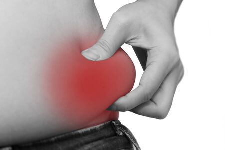 isolated woman measuring her belly fat with her handsの写真素材