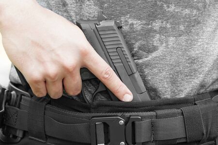 close up on a man holding a gun in trousers