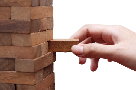 Isolated hand pull the wooden block game out of the wooden Jenga towerの写真素材
