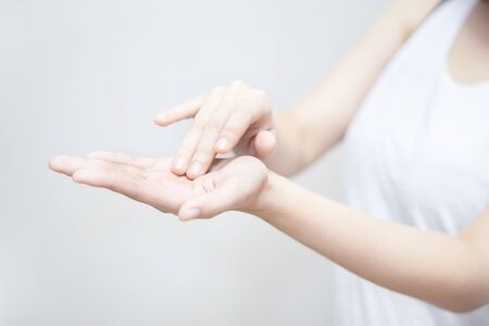 Isolated Asian Woman Applying Moisturizer on Her Handの写真素材