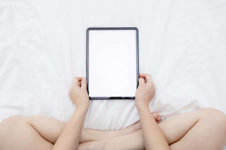 Top View of Asian Woman Watching Her  Blank Tablet with Empty Space on the Bedの写真素材