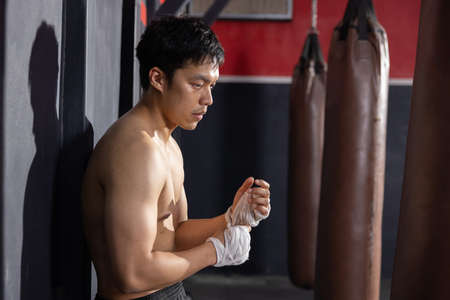 Asian Boxer Wrapping His Hands Before Thai Boxing Trainingの写真素材