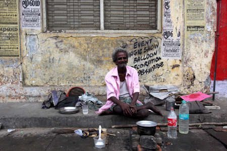 Pondicherry-Tamil Nadu, India-26 April 2012, An eldery homeless man sitting on the street.   With kitchenware and water for cooking, He used this area as a home.のeditorial素材