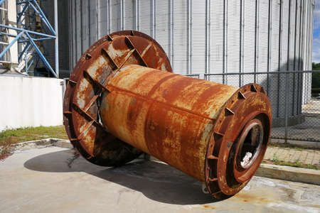 Rusting large machine parts placed outdoors in a factory areaの写真素材