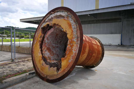 Rusting large machine parts placed outdoors in a factory areaの写真素材