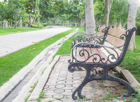 Old wooden bench in the park with jogging road in front.の写真素材