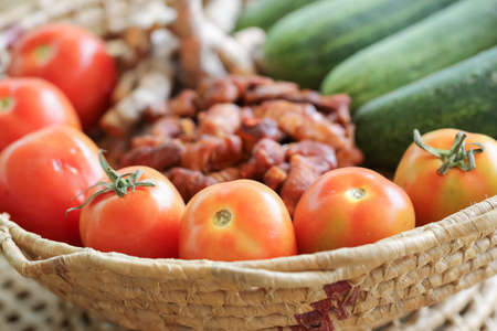 Red tomatoes with cucumber and galangal, tamarind fruit basket.の写真素材