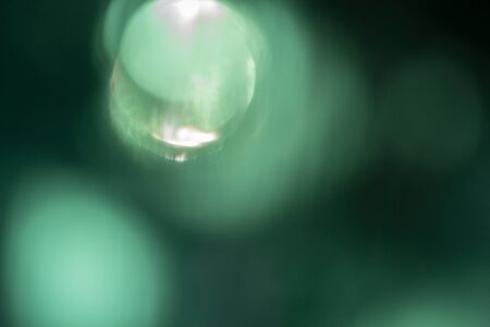 Green background, taken through a green filter in the light toward the sun, adjusting the image to be blurred a white light in the center.の写真素材