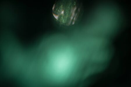 Green background, taken through a green filter in the light toward the sun, adjusting the image to be blurred a white light in the center.の写真素材