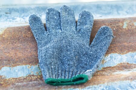 Gloves made of gray fabric The old is used. On rusted old zinc roofing sheetの写真素材