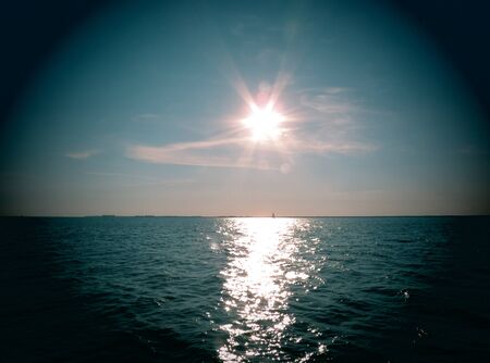 The sun on the water of the Wadden Sea. Looking through binoculars.