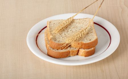 Two slices of wheat bread with two wheat stalks on a plateの写真素材
