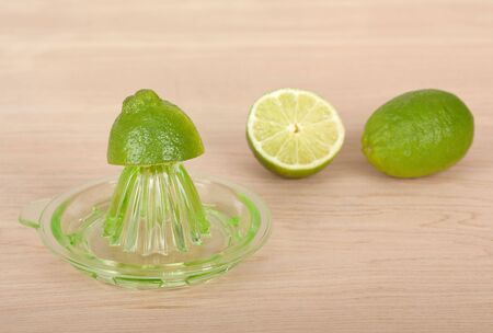 Juicer with two limes on a wooden tableの写真素材