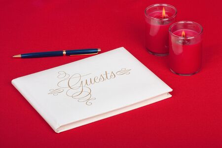 Wedding guest book with pen and candles on a red backgroundの写真素材