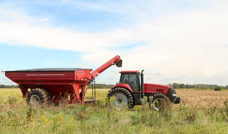 Red farm tractor and wagon in  a farm fieldの写真素材
