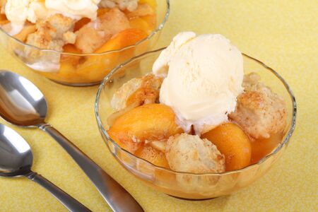 Two bowls of peach cobbler with ice cream on topの写真素材