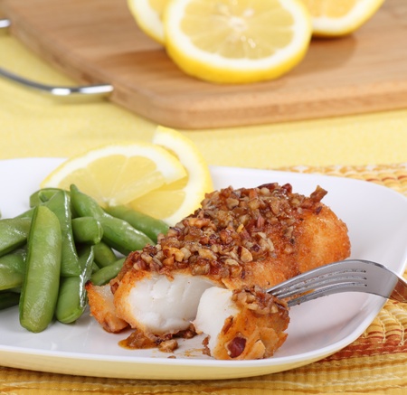 Pecan baked fish fillet with snap peas and lemon slicesの写真素材