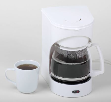 Cup of coffee next to a coffee maker on a white backgroundの写真素材