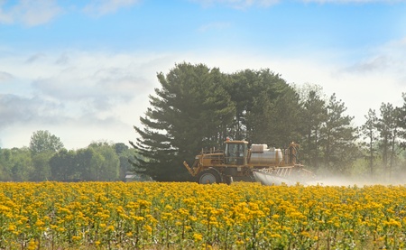 Agricultural spray truck spreading chemicals on a farm fieldの写真素材