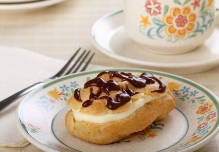 Cream filled eclair with chocolate icing on a plateの写真素材